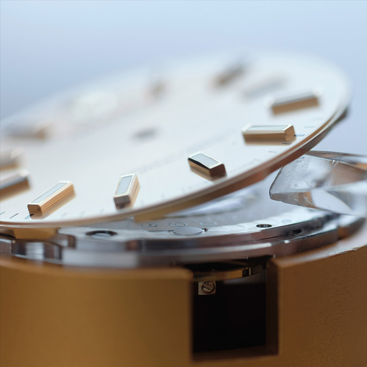 Bei einer zerlegten Rolex Uhr wird das Zifferblatt vorsichtig angehoben
