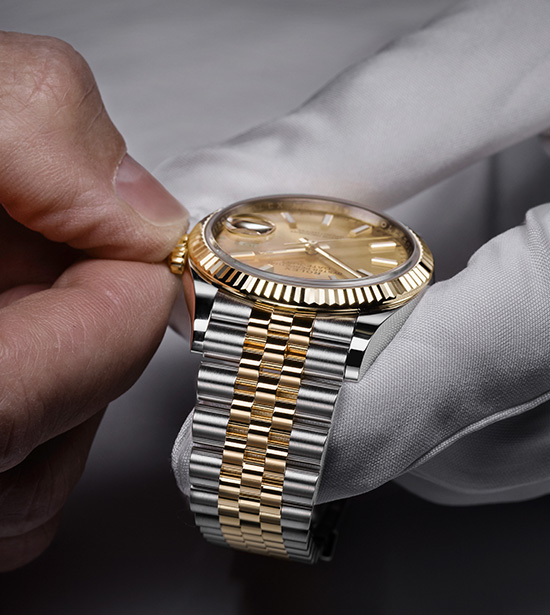 Eine Rolex Uhr wird von einem Mitarbeiter vom Service durch Drehen der Krone richtig eingestellt