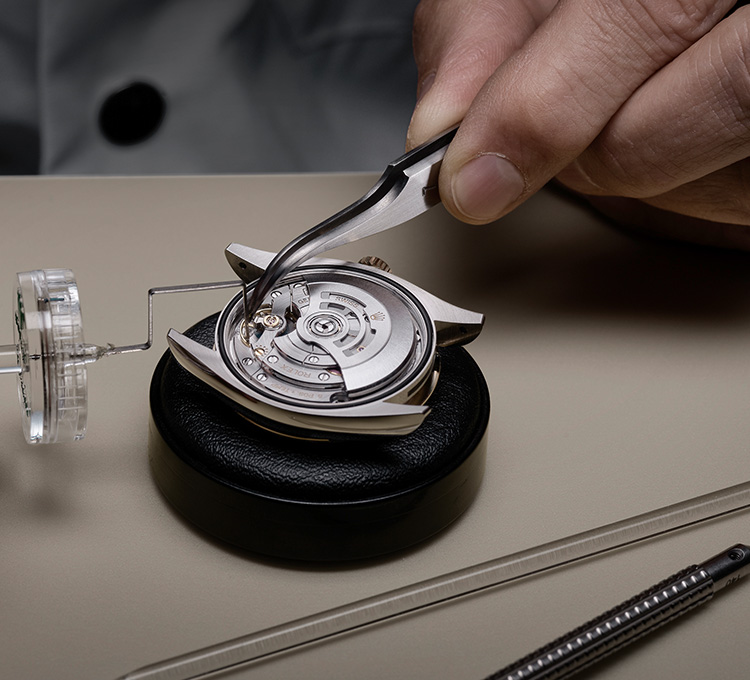 Ein Uhrmacher zieht eine Schraube am Werk einer Rolex Uhr fest
