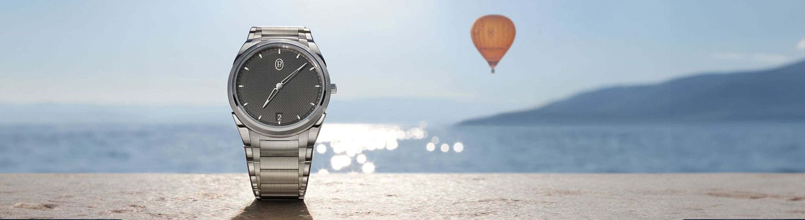 Eine Uhr von Parmigiani auf einem Stein mit dem Meer im Hintergrund